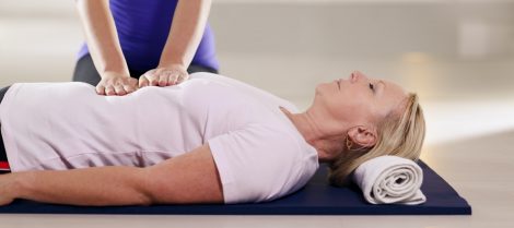Young Therapist Doing Reiki Therapy To Senior Woman